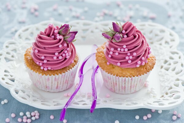 En una bandeja blanca hay cupcakes con crema rosa