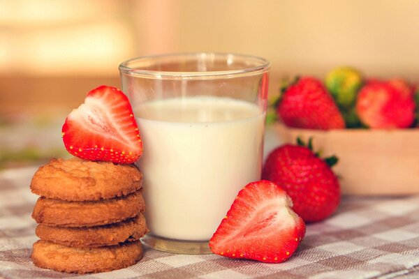 Neben einem Glas Milch liegen Kekse und Erdbeeren