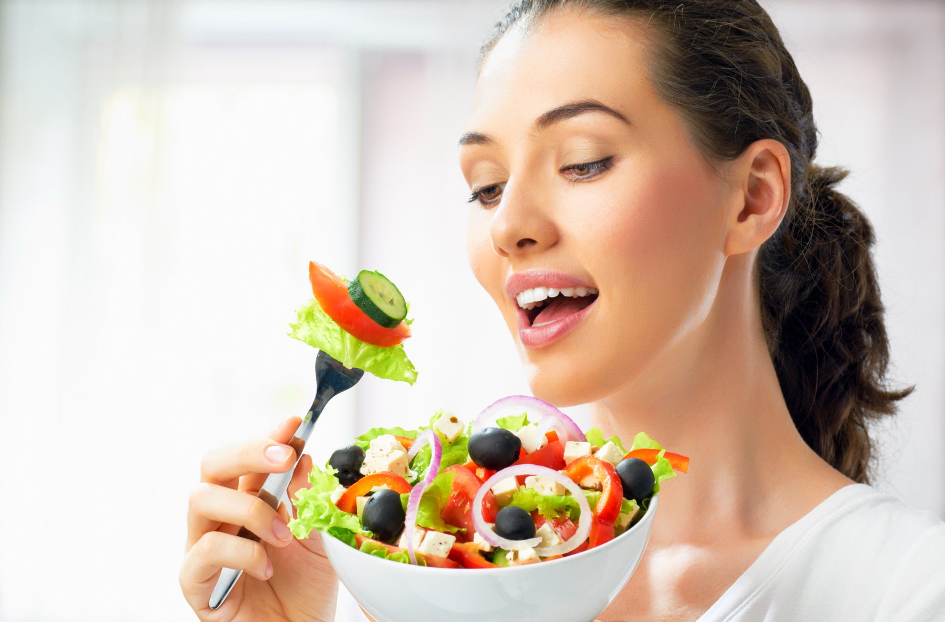 ragazza capelli castani piatto forchetta insalata verdure fascino cetrioli olive cipolle formaggio pomodori