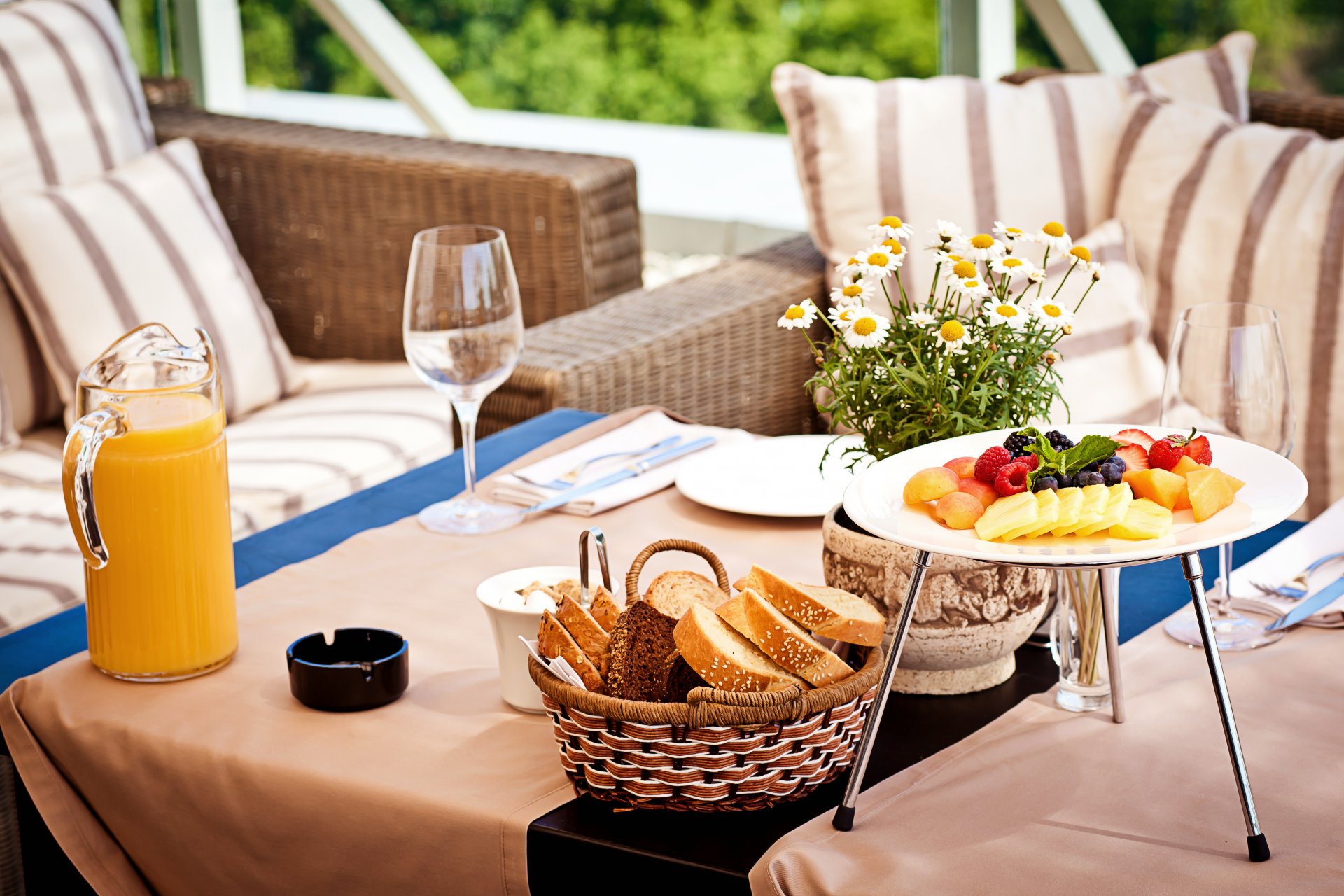 nourriture petit déjeuner jus orange pain fruits abricots ananas mangue baies bleuets framboises fraises table vase marguerites servir verres à vin assiettes