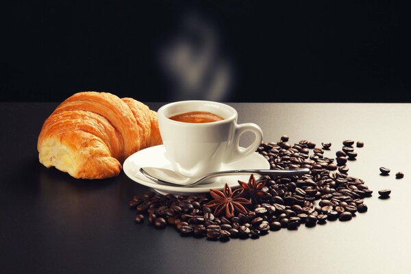 A cup of coffee with a croissant