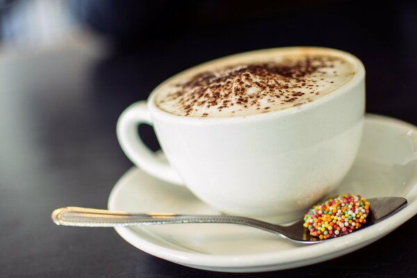 Cappuccino with foam and a spoon on a saucer