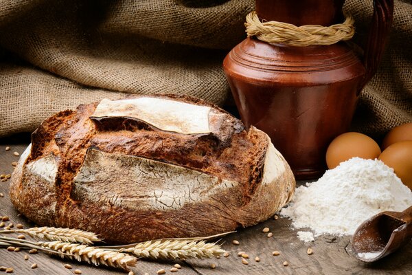 Pane fresco fatto in casa sul tavolo. Grani di spighe, farina con uova