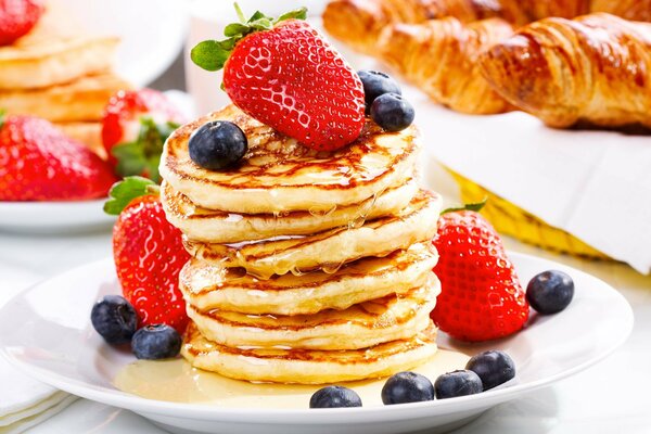 A plate of pancakes with strawberries and blueberries