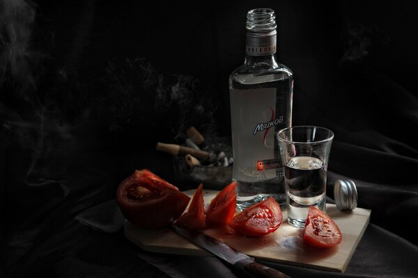 Vodka con tomates sobre un fondo negro