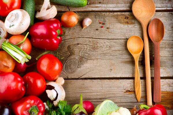 Cuillères en bois et légumes sur une table en bois