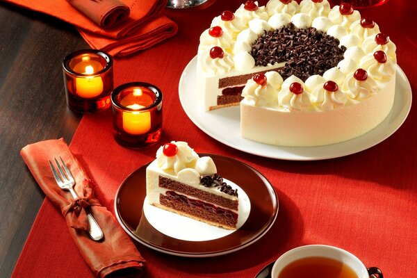 Thé avec gâteau sur une nappe rouge aux chandelles