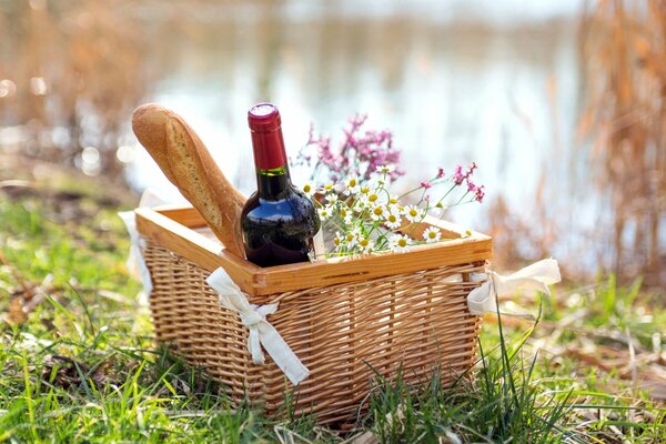 Picnic basket with wine and baguette on the shore