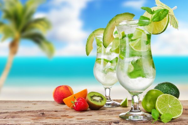 Two mojito cocktails with umbrellas and berries and fruits