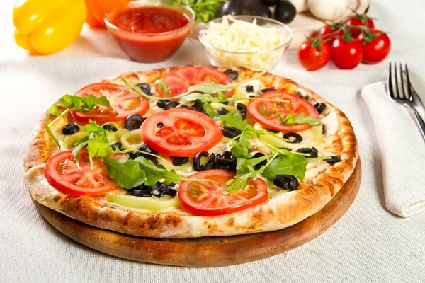 Pizza su un vassoio di legno con pomodori e olive