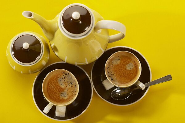 Deux tasses de café avec bouilloire sur la table jaune