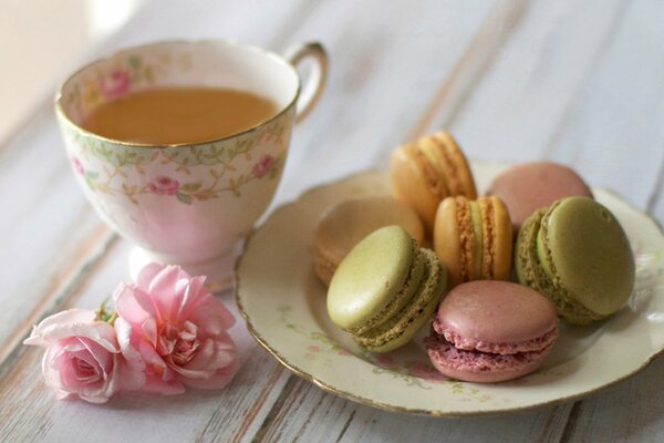 Couple de thé avec des roses et des biscuits macaron