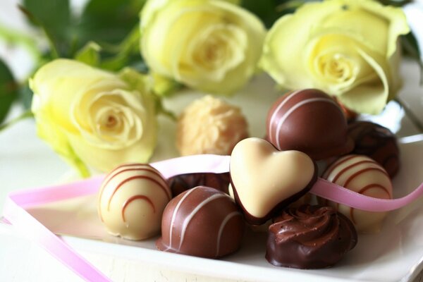 Bonbons au chocolat blanc et au lait dans une assiette sur un fond de roses