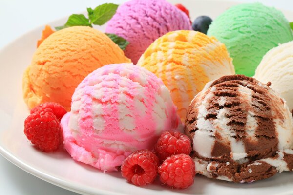 Colored ice cream balls on a plate with raspberries