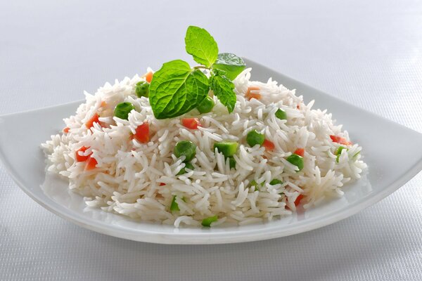 Square plate of rice with vegetables and herbs