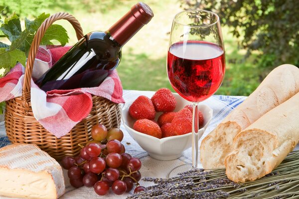 Baguette, Erdbeeren, Trauben, ein Glas Rotwein in der Natur