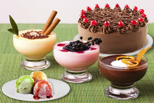 Три кремовых десерта, шарики мороженного на тарелке и шоколадный торт, украшенный ягодами на блюде