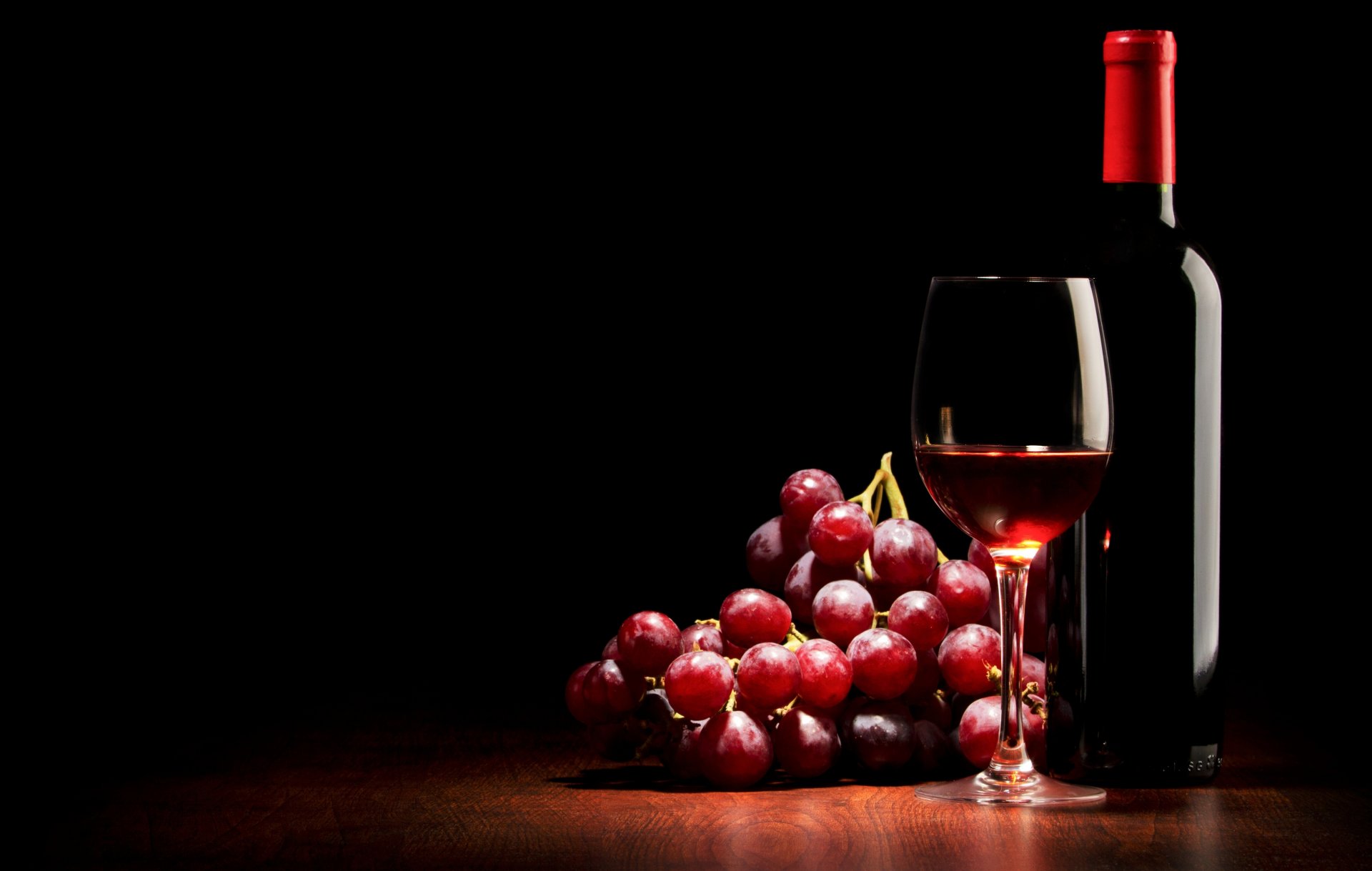 wine red grapes a bottle glass black background