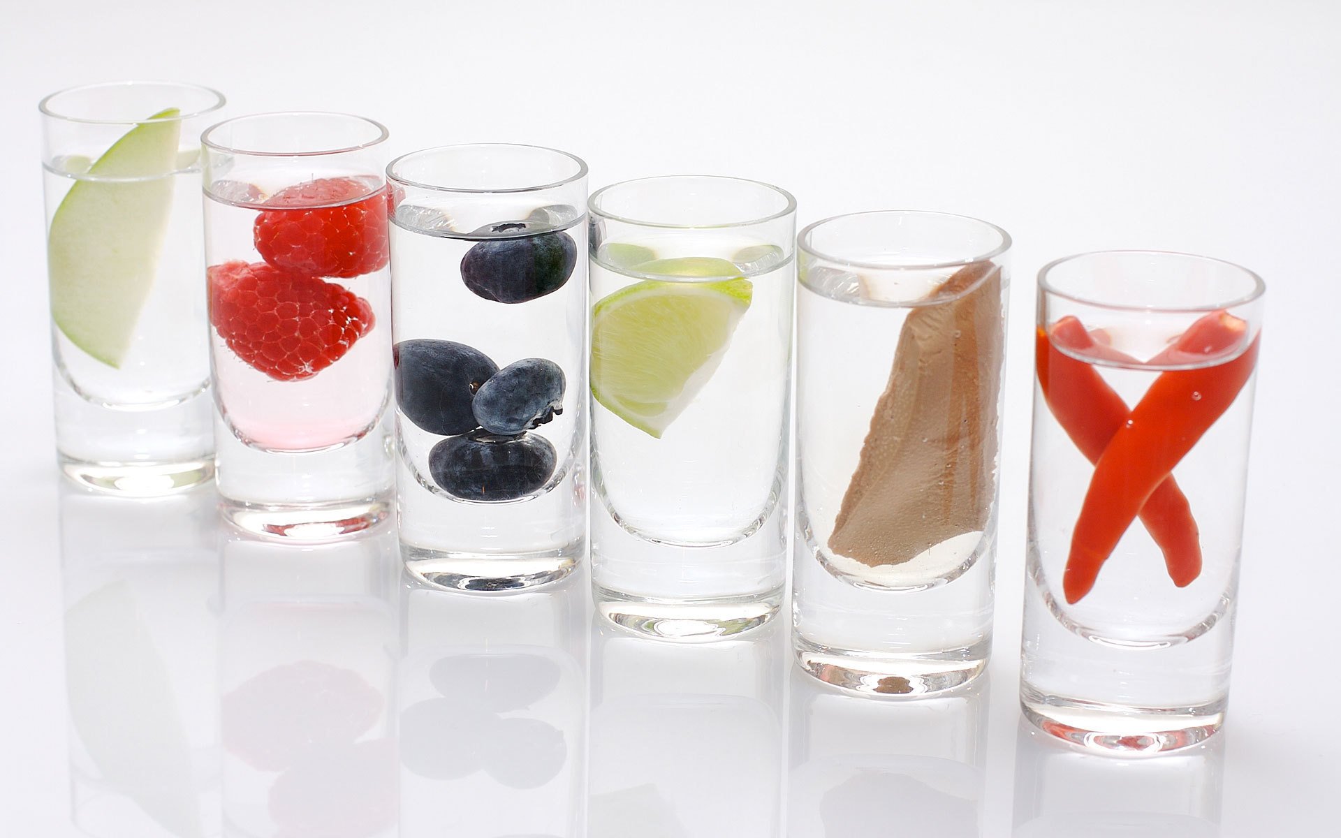 white background macro glasses shot glasses stacks water liquid lemon apple pepper mushroom raspberry olives olive