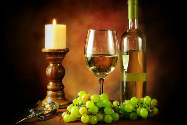 A bottle of wine with a glass and grapes