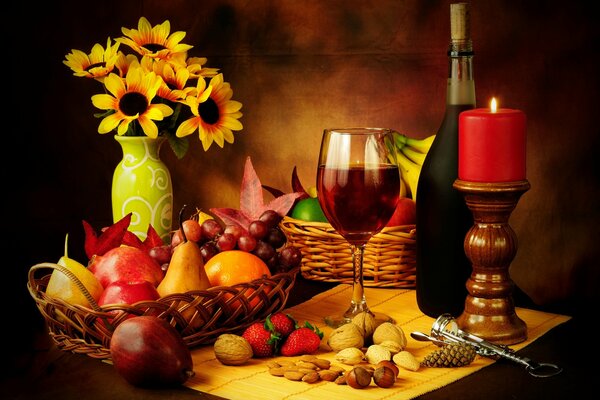 Stillleben von Körben mit Birnen, Äpfeln und Bananen, Walnüssen und Haselnüssen, die mit einem Glas Wein, einer roten dicken Kerze am Leuchter und einer Flasche Wein auf dem Tisch stehen