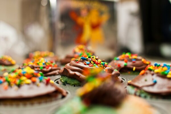 Tapas de cupcakes adornadas con crema de chocolate y chispas de colores