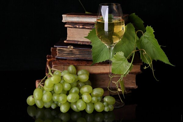 Бокал белого виноградного вина и стопка книг