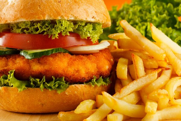 Hamburger with thick chop, juicy greens, tomatoes, onions surrounded by French fries