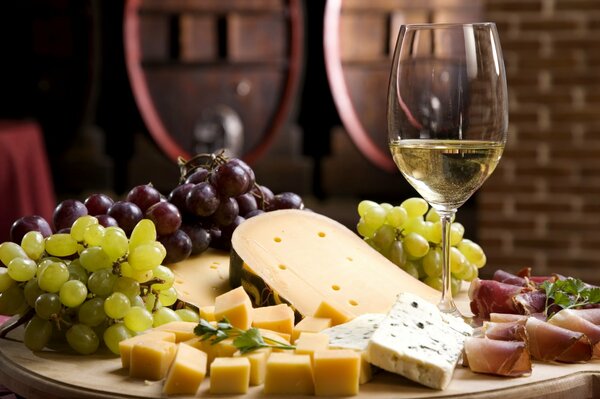 Dans un verre de vin blanc, près de raisins et de fromage