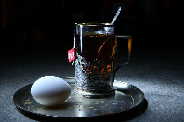 Tasse de thé et oeuf sur le plateau