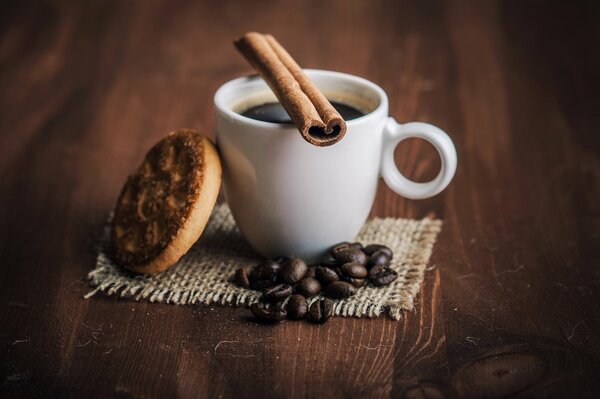 A cup of coffee with cinnamon and cookies