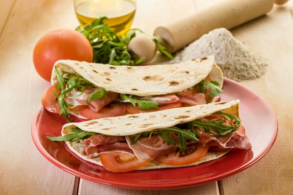 Ein Teller mit Pita, in dem das Fleisch Tomaten und Grüns enthält