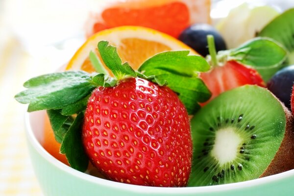 Kiwi, fraise et orange placés dans un bol