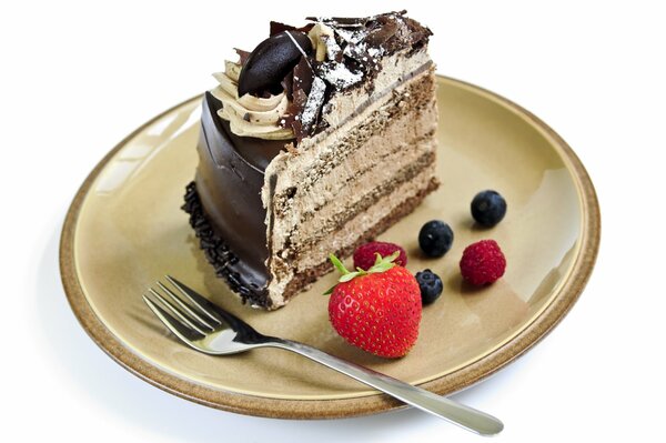 Ein Stück Kuchen mit Schokoladenglasur und Sahne neben den Beeren auf der Untertasse liegen