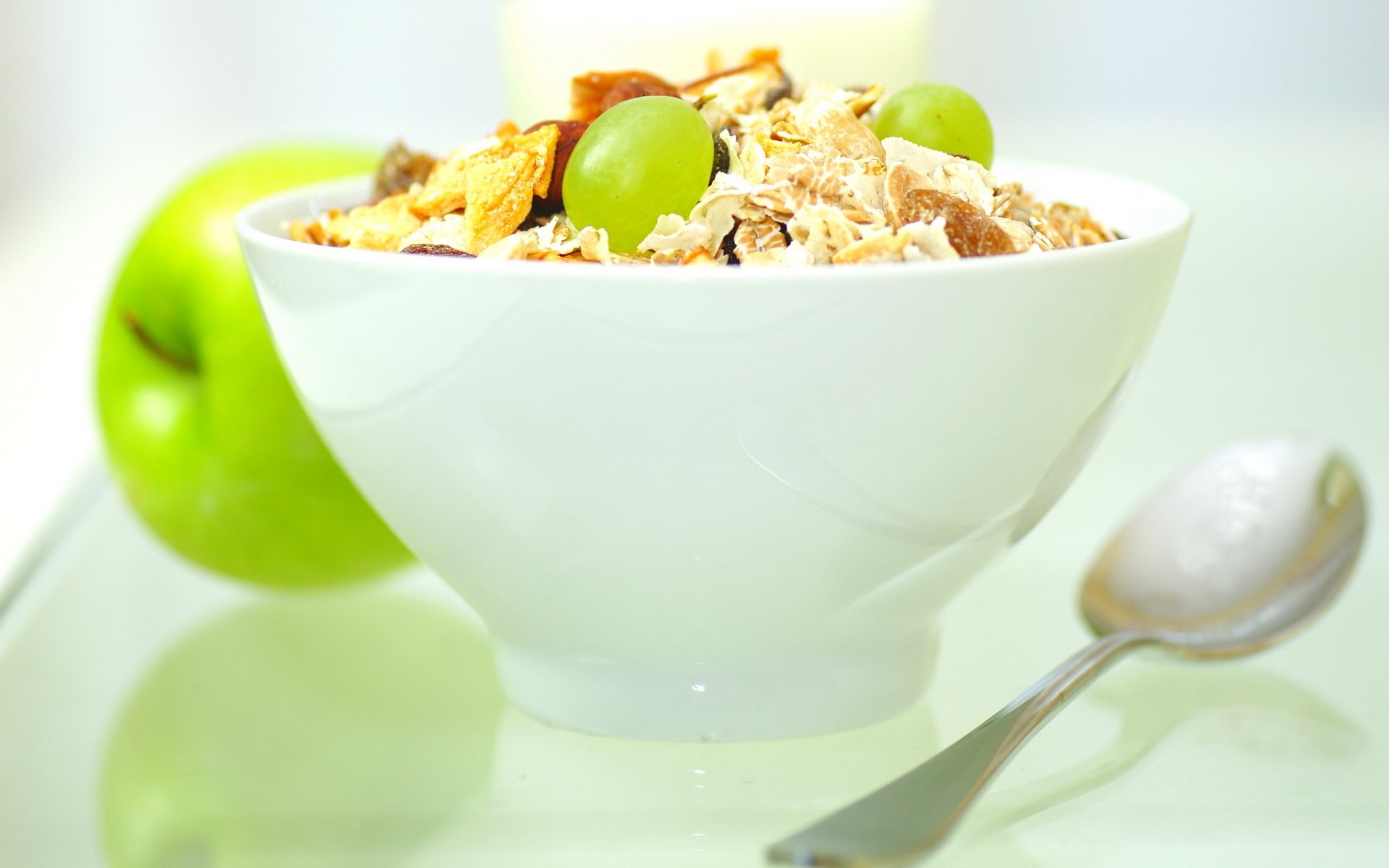 comida dulce granola fruta uvas manzana desayuno ligero cereales pasas cuchara plato fondo blanco