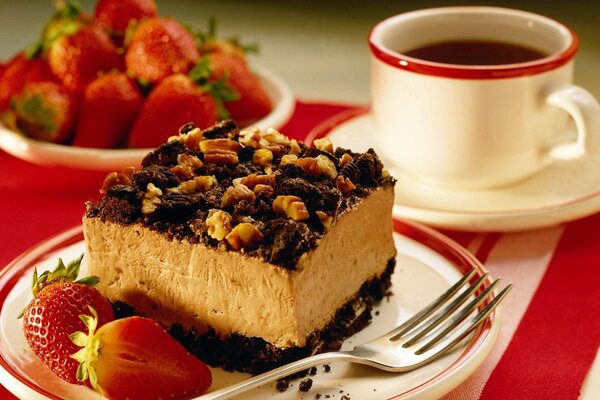 Gâteau aux noix et fraise sur soucoupe, tasse blanche