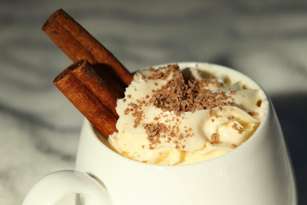 Taza con la bebida caliente adornada con la crema y el chocolate rallado