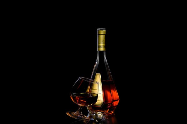 Bottiglia di cognac su sfondo nero e bicchiere di vino accanto