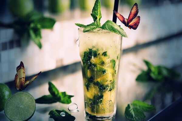 Cóctel de Mojito sobre un fondo de verdes, limas y mariposas