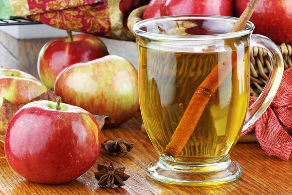 Succo di mela in un bicchiere con una cannuccia sul tavolo con le mele