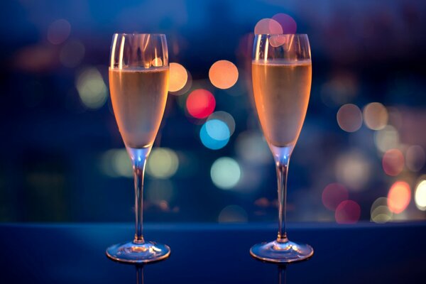 Two glasses of champagne on the table against the background of the lights of the evening city