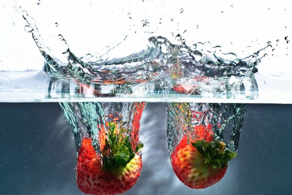 Reife Erdbeeren, die ins Wasser fallen