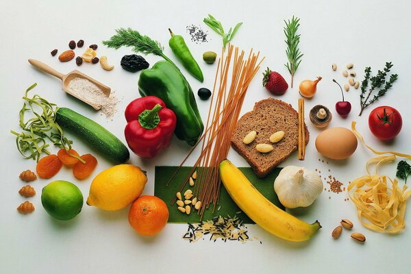 Auf weißem Hintergrund liegen Gemüse, Obst Brot Getreide