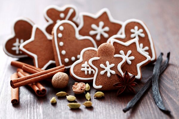 Biscuits de Noël sous la forme de flocons de neige, étoiles et coeurs avec des bâtons de cannelle et des noix sur une table en bois