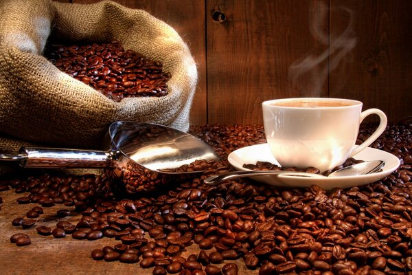 Chicchi di caffè sparsi sul tavolo con una tazza di caffè