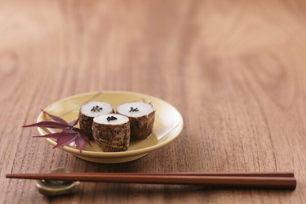 Sushi auf einem Teller und mit Stäbchen auf einem Tisch