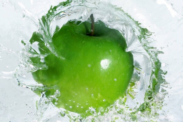 A green apple in the water in a macro shot