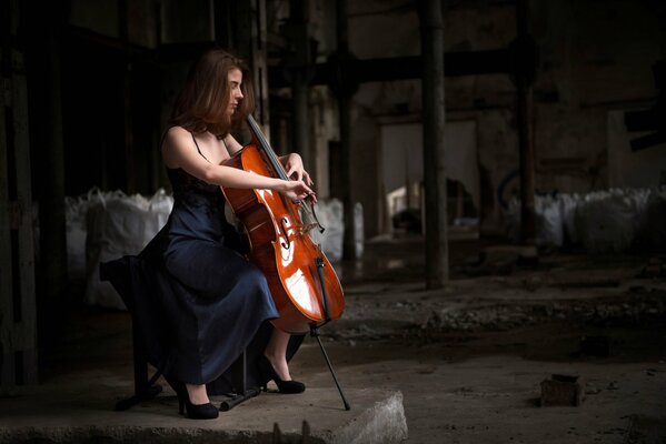 Девушка в чёрном платье сидит с виолончелью
