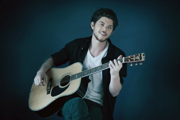 A young man plays the guitar