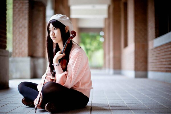 A girl with a violin sitting on the floor